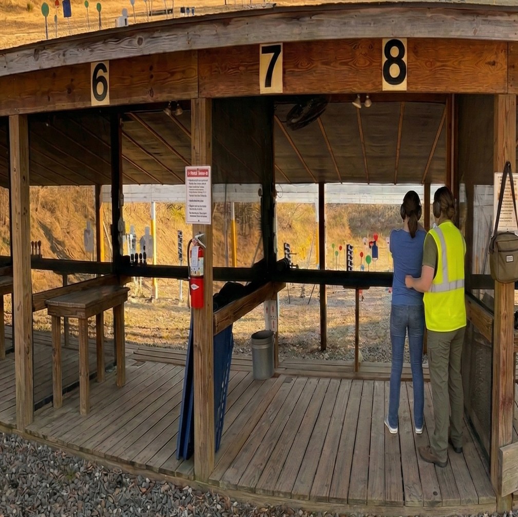 A Women on Target instructor coaching a shooter at the covered pistol stalls